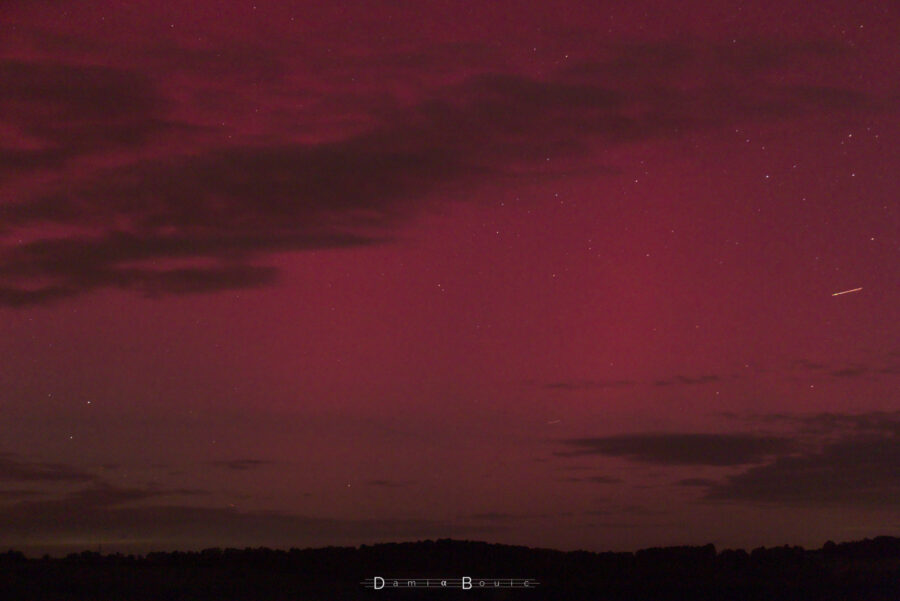 Photo grossie sur le fond du ciel, montrant de pâles lueurs rouges